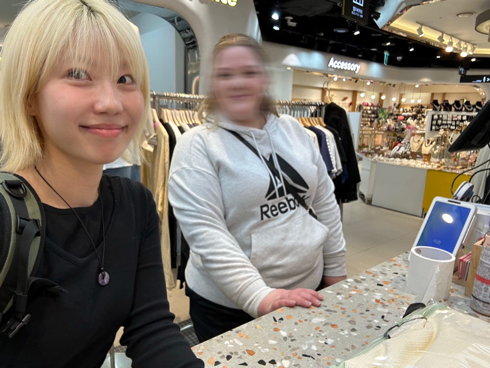 Eden at a store counter with a client, both smiling, in a Seoul shopping mall